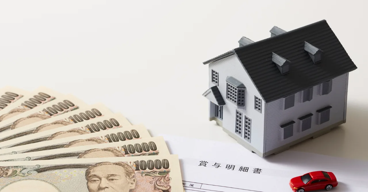 扇状に広げた一万円札、住宅の模型、賞与明細書と赤いミニカーを並べたイメージ写真。日銀の利上げが住宅ローンの変動金利・固定金利に届くまでの経路と時間差を解説する記事のヘッダー画像