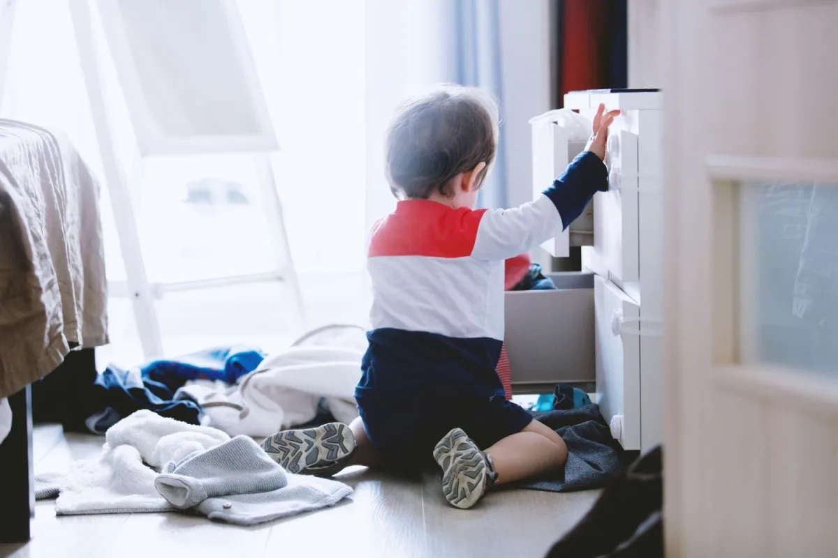子どもが部屋の家具を触って荷物が散らかっている様子