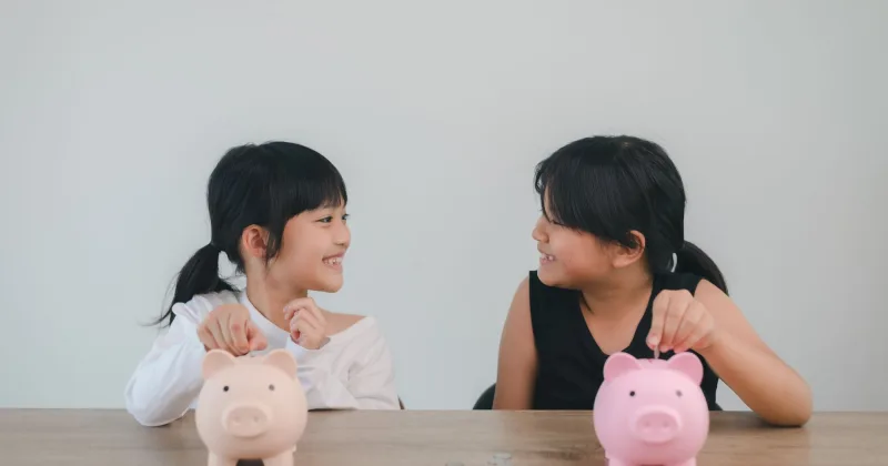 貯金箱にコインを入れる子どもたち
